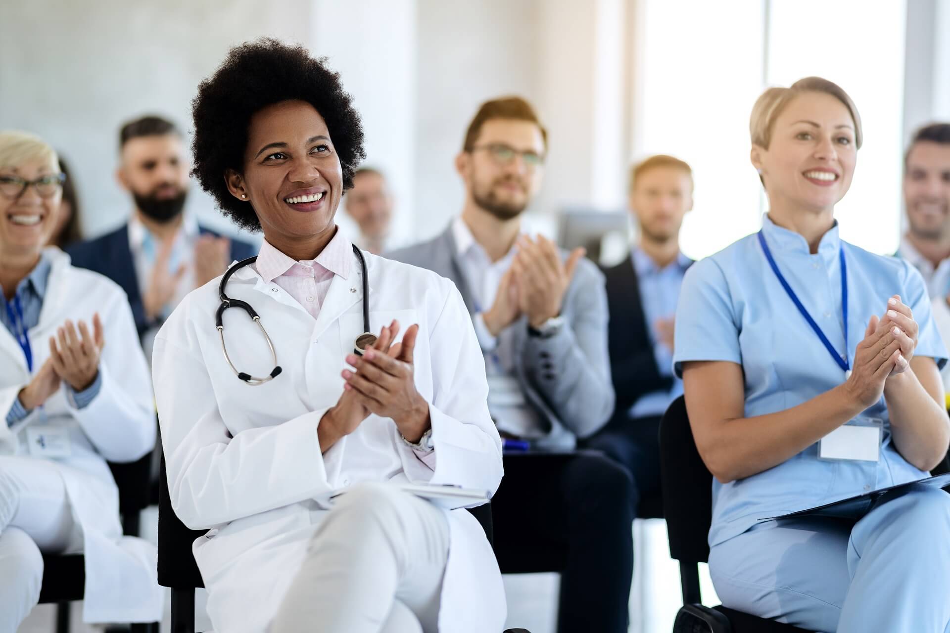 happy-african-american-doctor-applauding-while-attending-healthcare-seminar